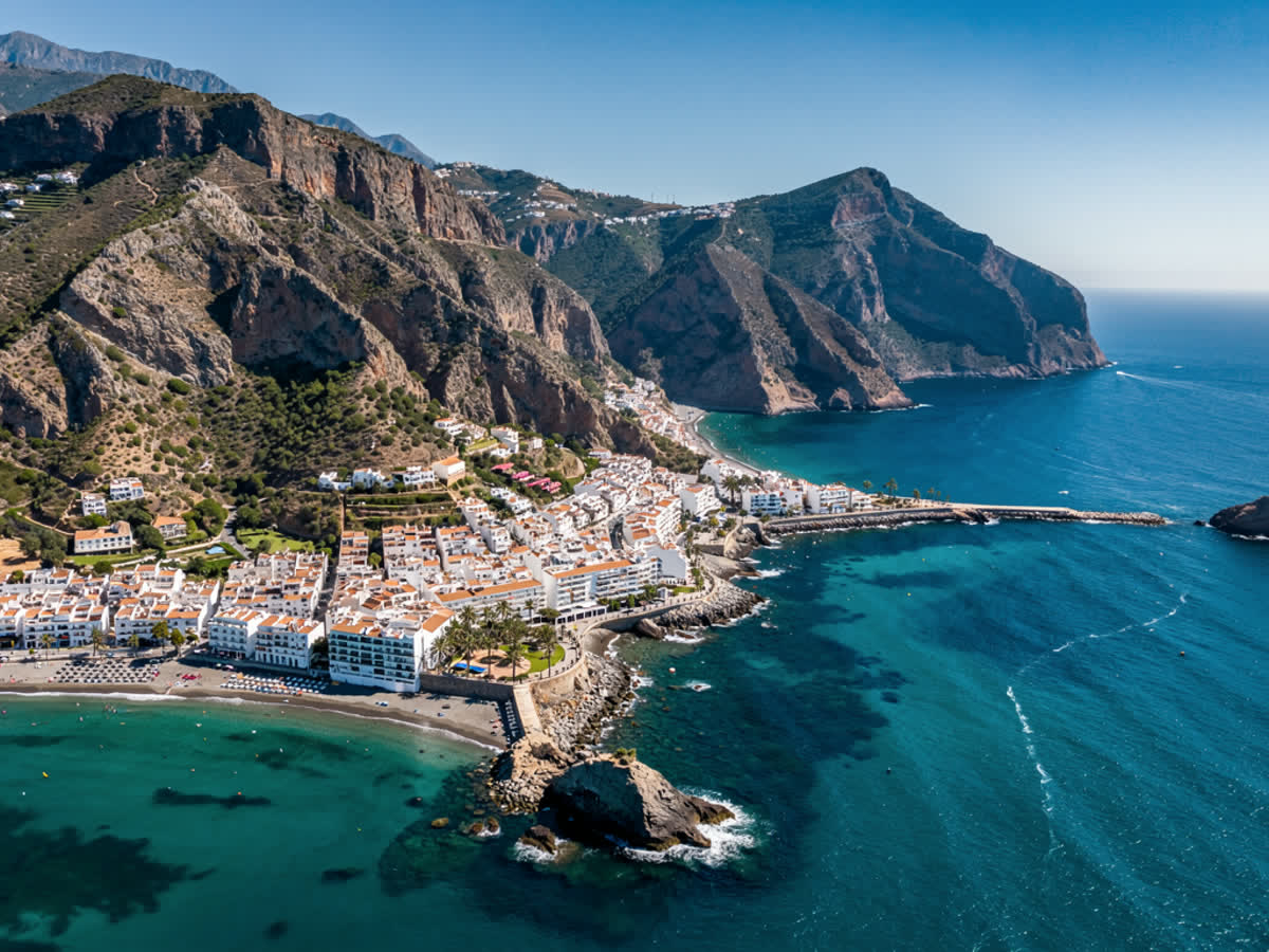 Aerial view of Almuñécar coastline with mountains behind, blue sky